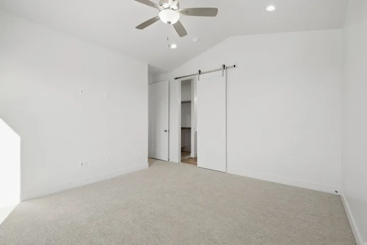 Vaulted ceiling, carpeted flooring, ceiling fan, recessed lighting, barn door entry