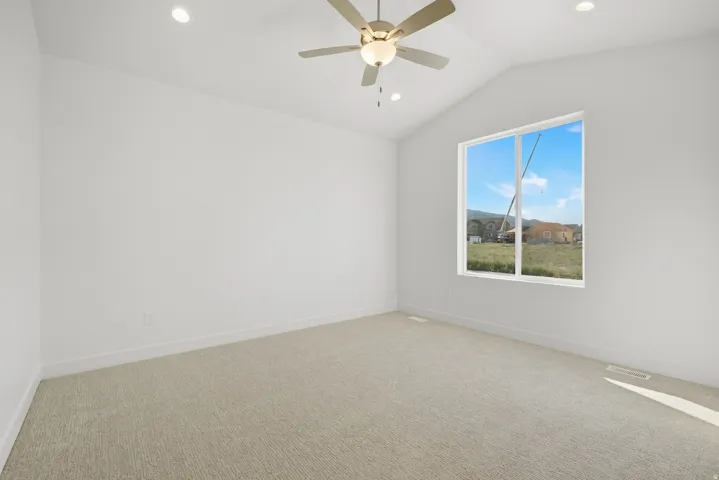 Vaulted ceiling with an integrated ceiling fan, recessed lighting, expansive window, and light-colored carpeting