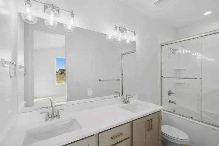Dual sink vanity with white countertop, chrome fixtures, and shaker-style cabinetry