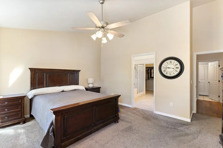 Vaulted ceiling with an attached ceiling fan, carpet flooring, and neutral wall tones