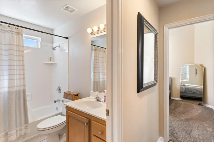 Bathroom featuring a single vanity, integrated sink, overhead lighting, and a shower-tub combination with a window