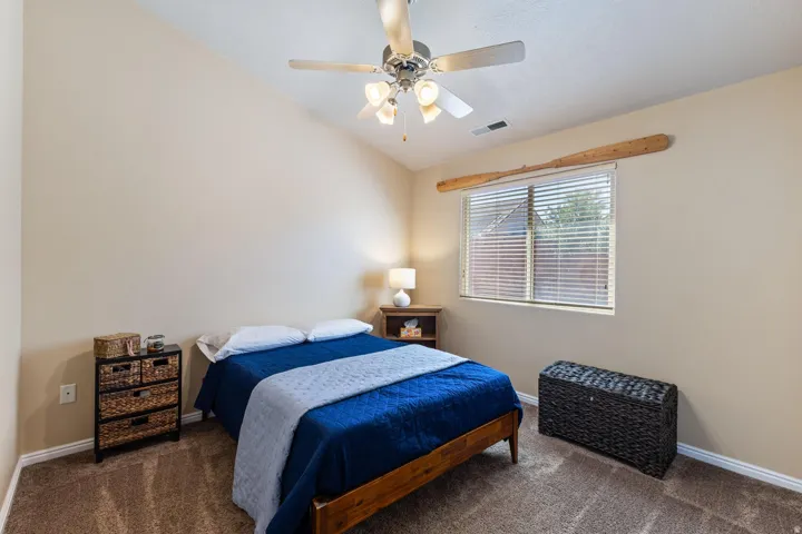 Vaulted ceiling with a ceiling fan, carpeted flooring, and a single window with horizontal blinds