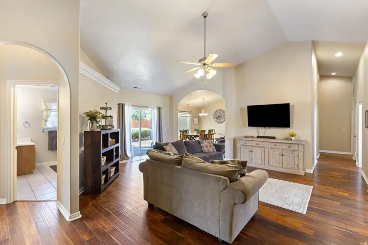 Vaulted ceiling with a ceiling fan, wood-finish flooring, sliding glass door to exterior, arched entryway, and recessed lighting
