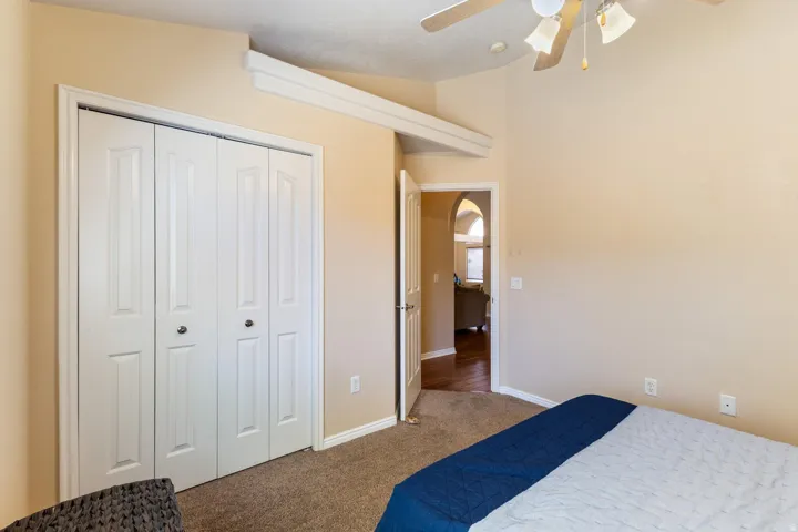 Vaulted ceiling with a ceiling fan, carpeted flooring, and bi-fold closet doors
