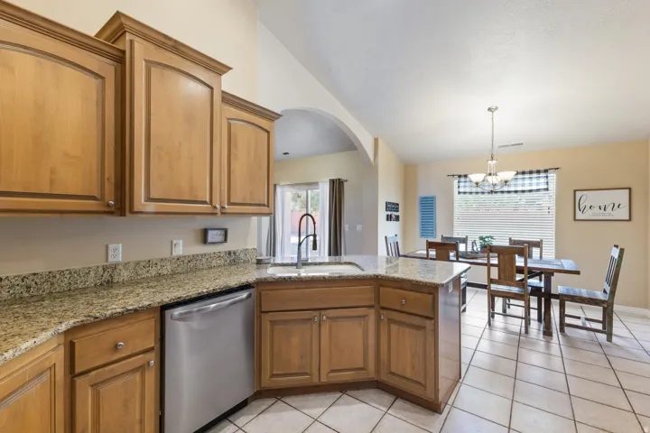 Kitchen featuring wood cabinetry, granite countertops, stainless steel dishwasher, and a black gooseneck faucet