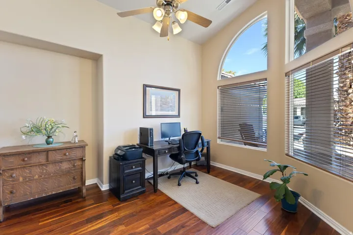Vaulted ceiling with a ceiling fan, wood-finish flooring, arched transom window, multiple windows with blinds