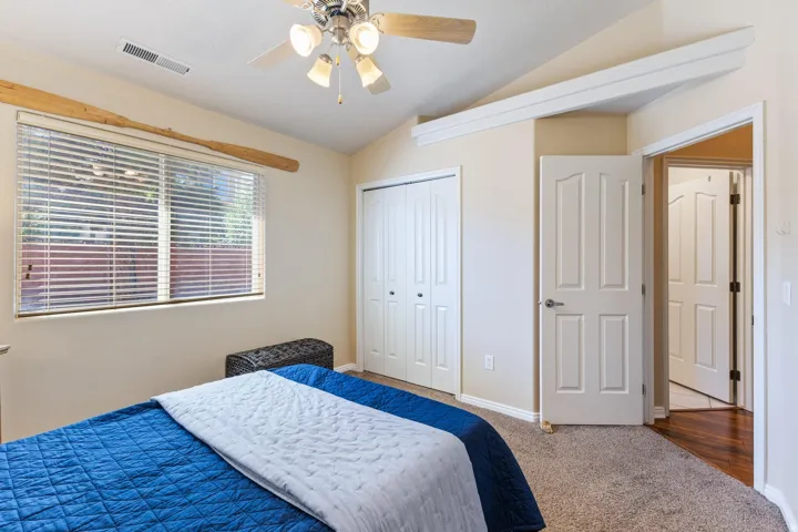 Vaulted ceiling with a ceiling fan, window with blinds, bi-fold closet doors, and light-toned carpeting