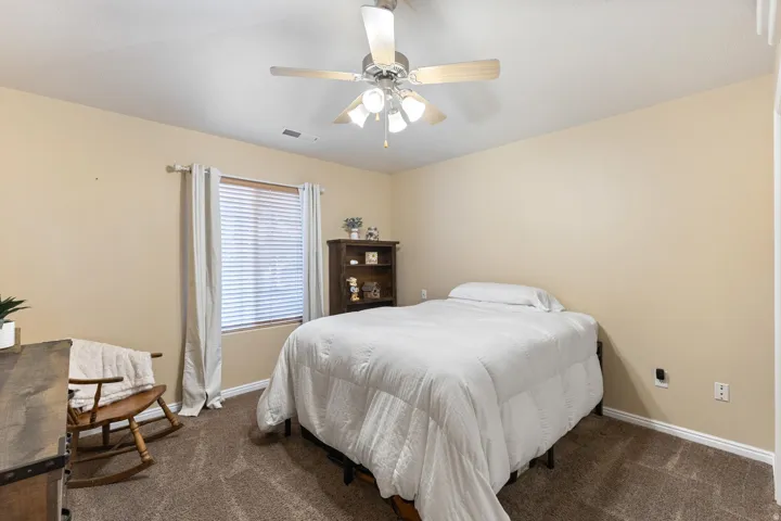 Carpeted flooring, ceiling fan with integrated lighting, and window with blinds