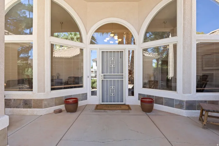 Arch-top entry with a decorative security screen door, side lights, and transom windows