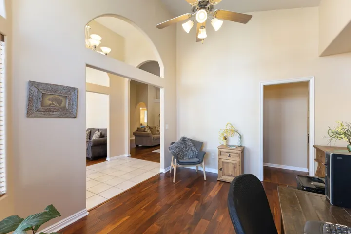 High ceilings with an architectural archway, wood-finish flooring, and a ceiling fan with integrated lighting