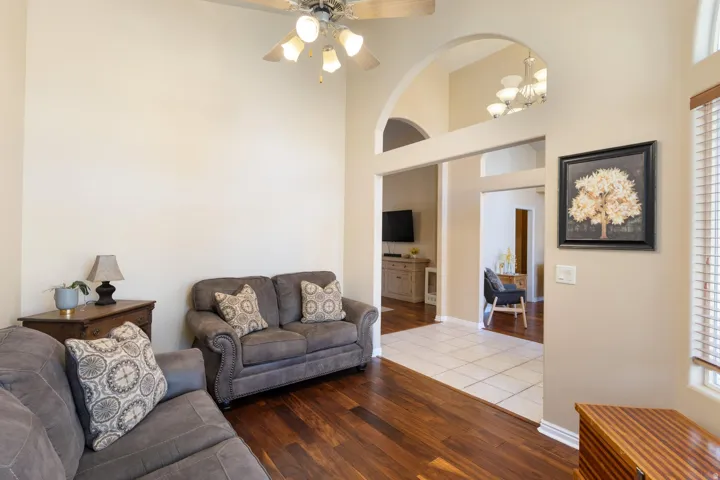 Vaulted ceiling with an attached ceiling fan, rich wood-finish flooring, and arched doorways