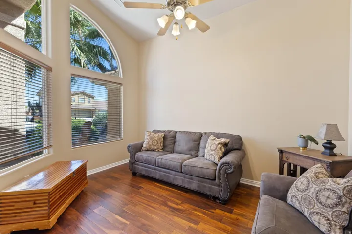 Vaulted ceiling with a ceiling fan, arched transom window, wood-finish flooring, and horizontal window blinds