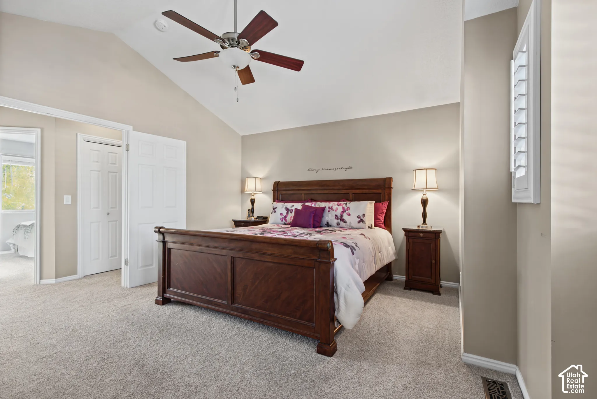 Vaulted ceiling with a ceiling fan, plush carpet, and white plantation shutters