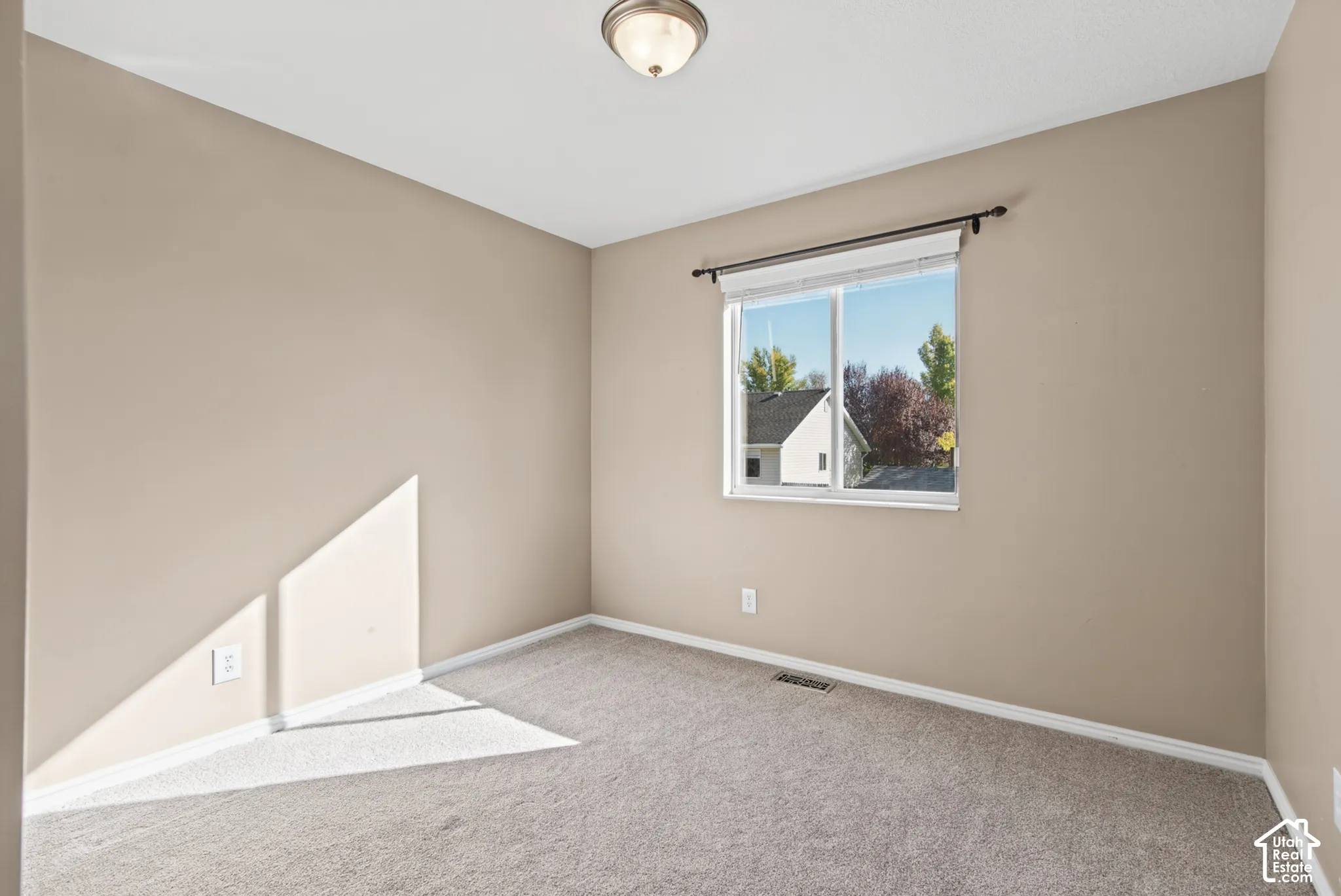 Carpeted flooring, neutral wall tones, recessed window with blinds, and ceiling-mounted light fixture