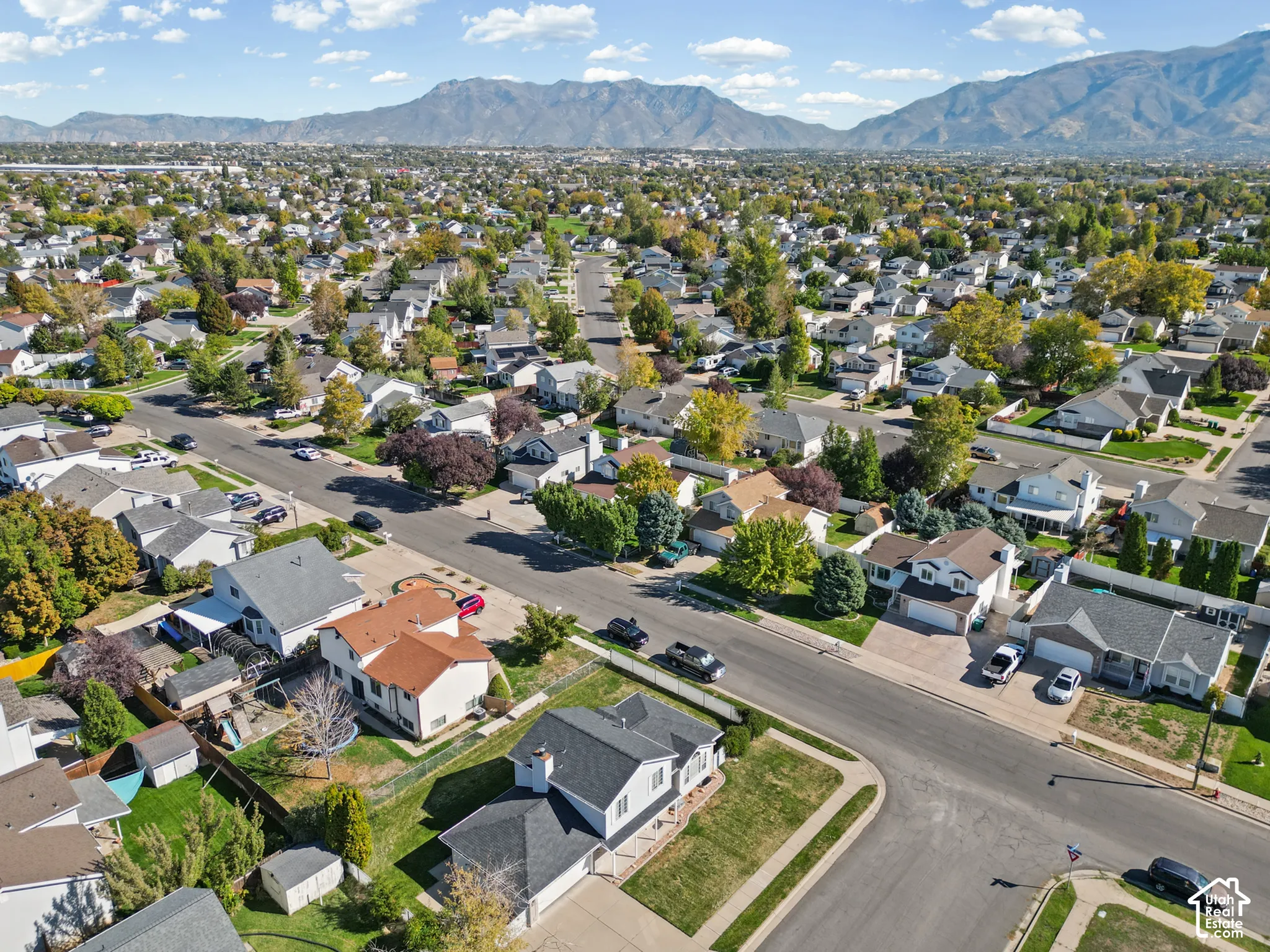 Residential neighborhood with established streets and mature trees, set against a mountain backdrop