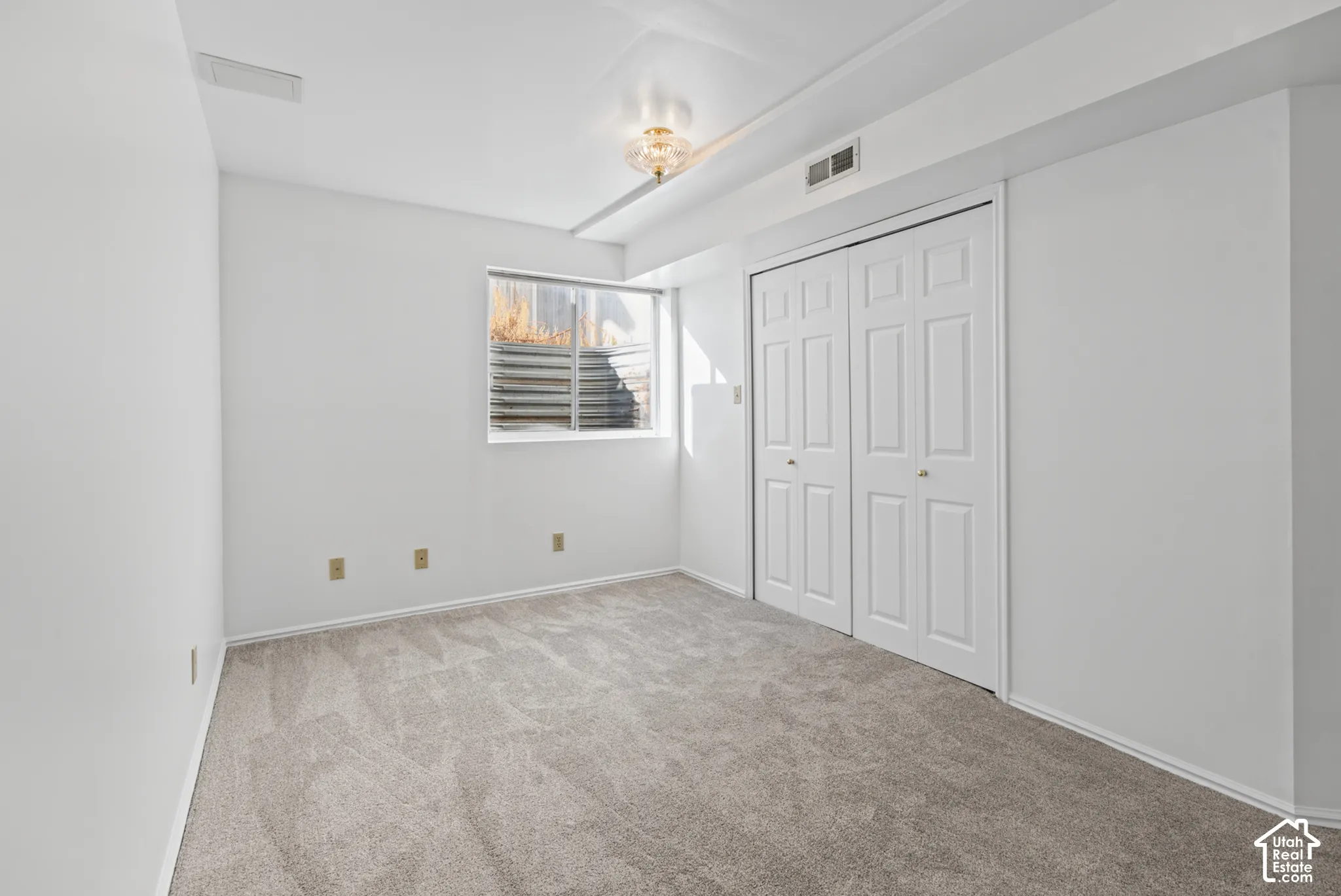 Wall-to-wall carpeting, window well, double bi-fold closet doors, recessed lighting, and wall-mounted light fixture