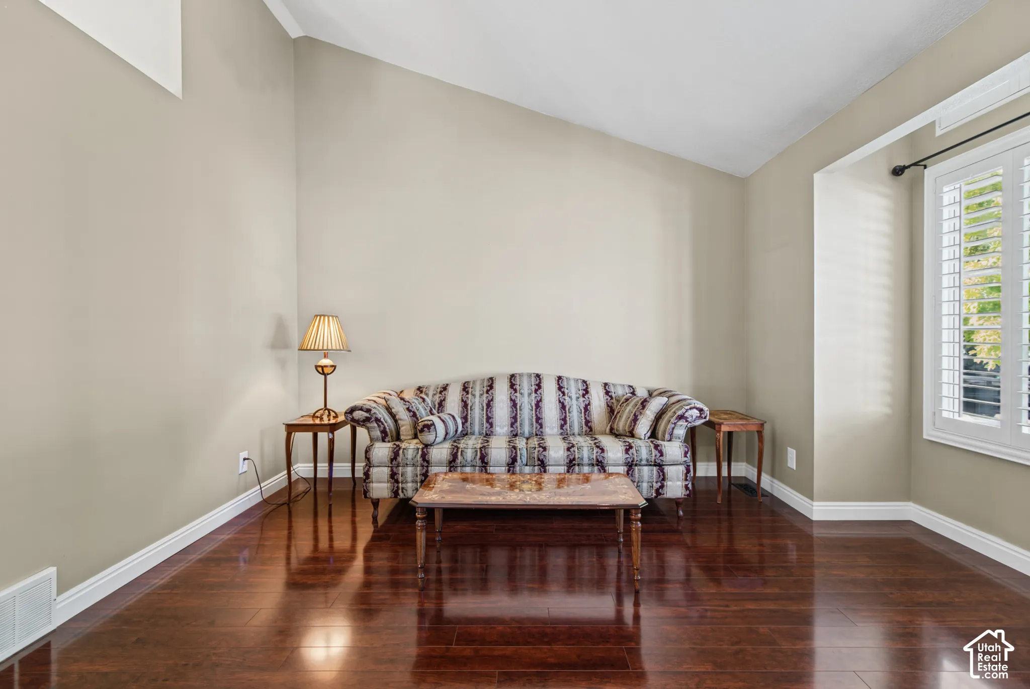 Wood-finish flooring, vaulted ceiling, white window shutters, and white trim