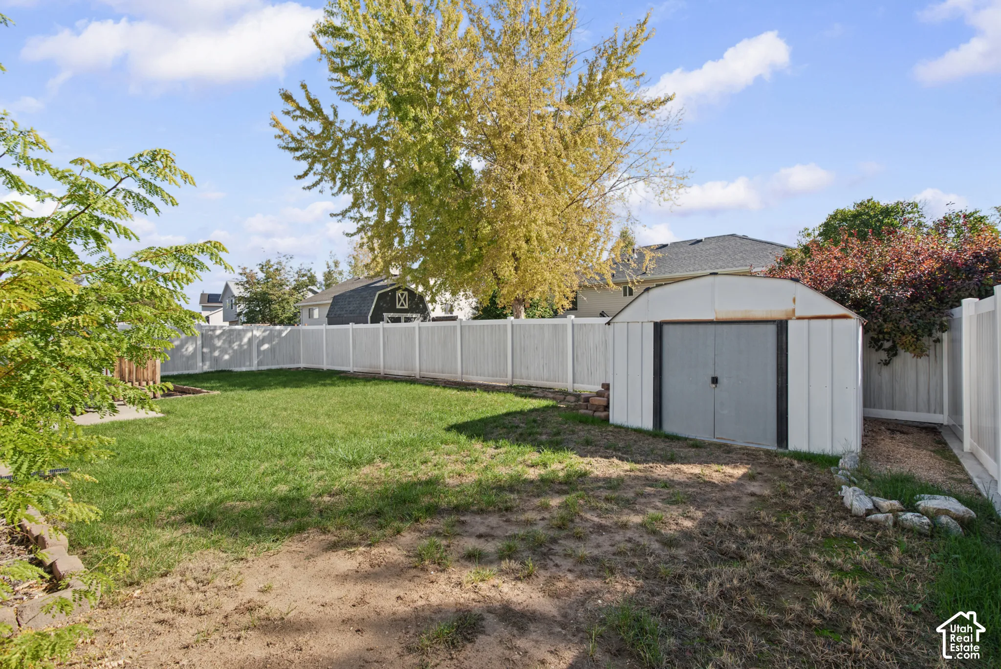 Fenced backyard featuring a manicured lawn and a storage shed