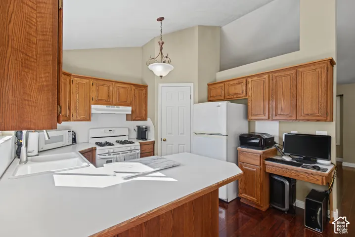 Kitchen featuring wood cabinetry, white countertops, built-in sink, and white appliances