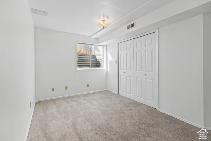 Wall-to-wall carpeting, window well, double bi-fold closet doors, recessed lighting, and wall-mounted light fixture