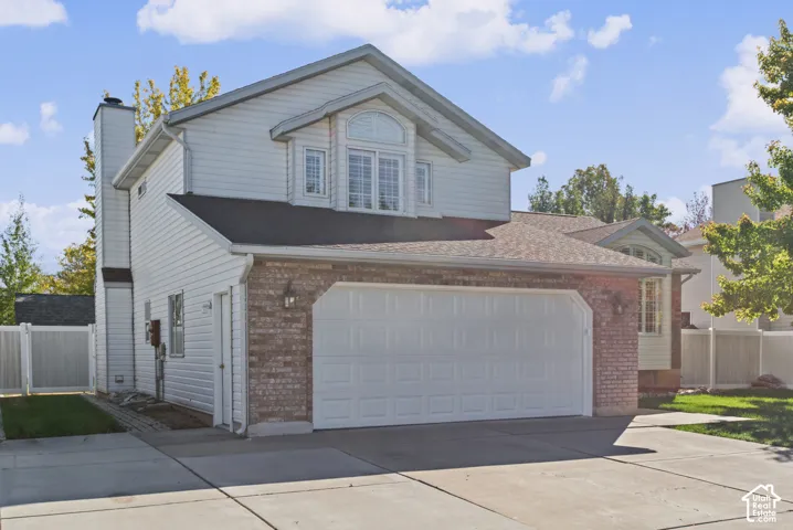 Two-story residence featuring a brick facade with horizontal siding, an attached two-car garage, and a concrete driveway