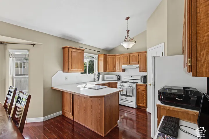 Kitchen featuring wood-finish cabinetry, white countertops, vaulted ceiling, and wood-finish flooring