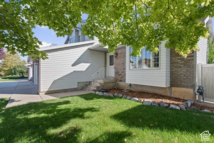 Exterior featuring brick and siding finishes, a bay window with plantation shutters, a concrete driveway, and a fenced yard