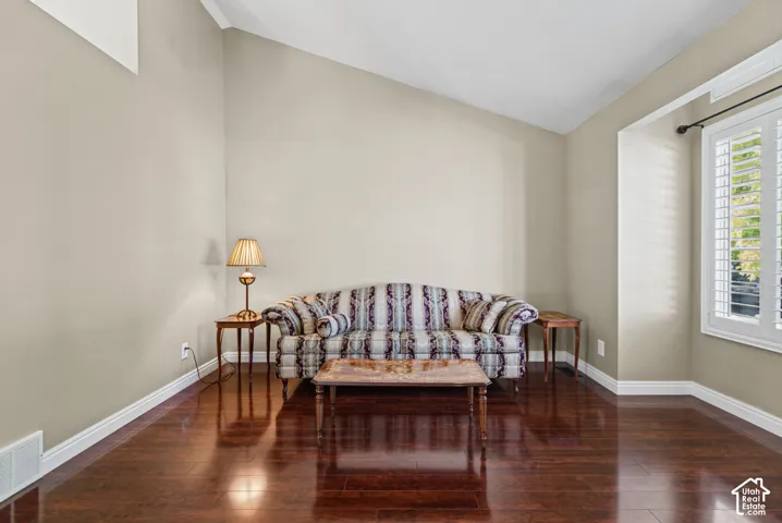 Wood-finish flooring, vaulted ceiling, white window shutters, and white trim