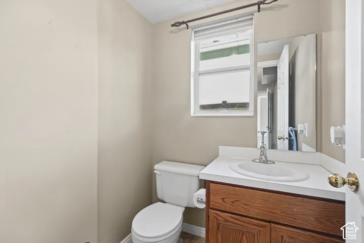 Compact half bath featuring a wood-finish vanity with an integrated sink, white porcelain toilet, and large framed mirror