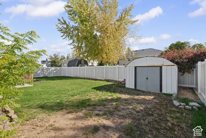 Fenced backyard featuring a manicured lawn and a storage shed