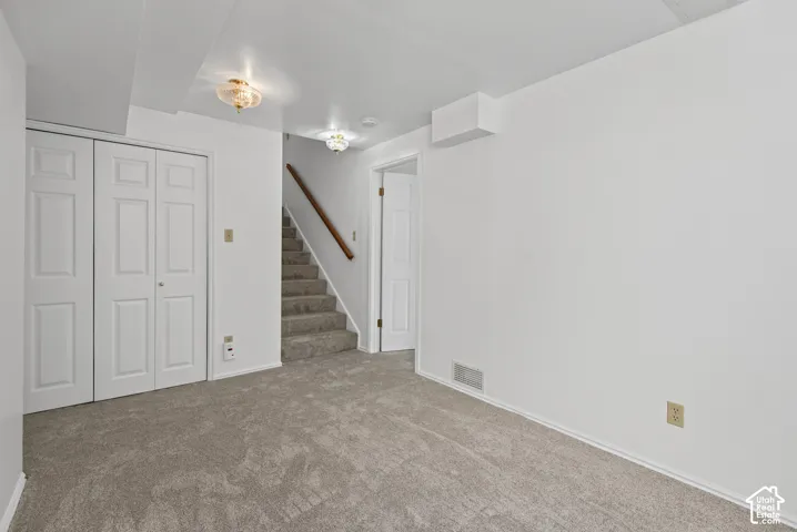 Carpeted flooring, white walls, bi-fold doors, and a wood handrail