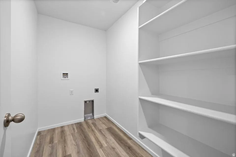 White walls, wood-finish flooring, built-in shelving, appliance hookups, and a contemporary doorknob