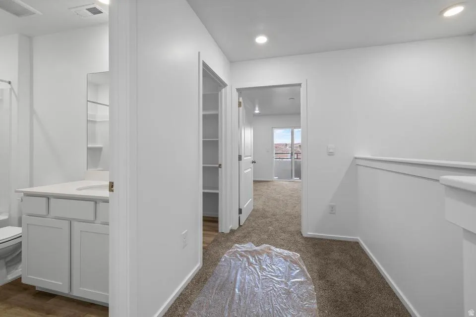 White vanity with integrated sink, built-in shelving, and neutral carpeting