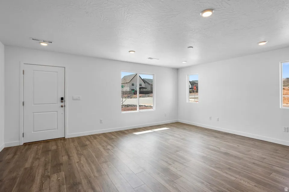 Recessed lighting, multiple windows, wood-finish flooring, white trim, and a white two-panel door
