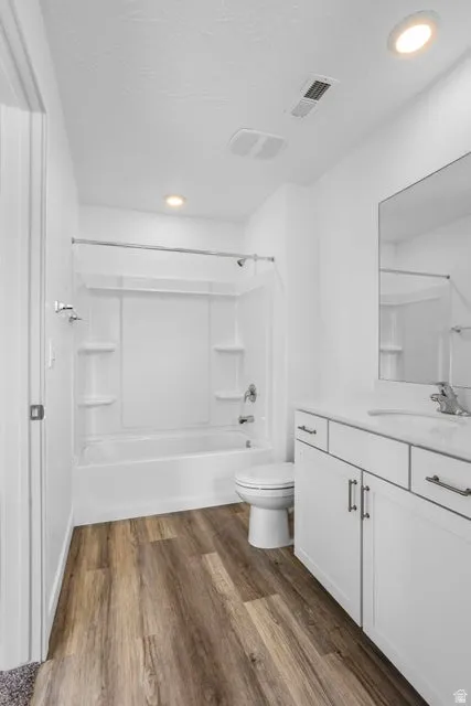 Wood-finish flooring with a white vanity featuring a polished countertop and an integrated sink