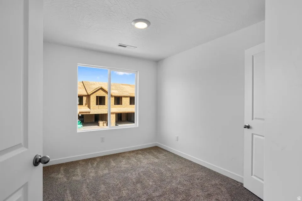 Recessed lighting, white walls, gray carpet flooring, and a large window
