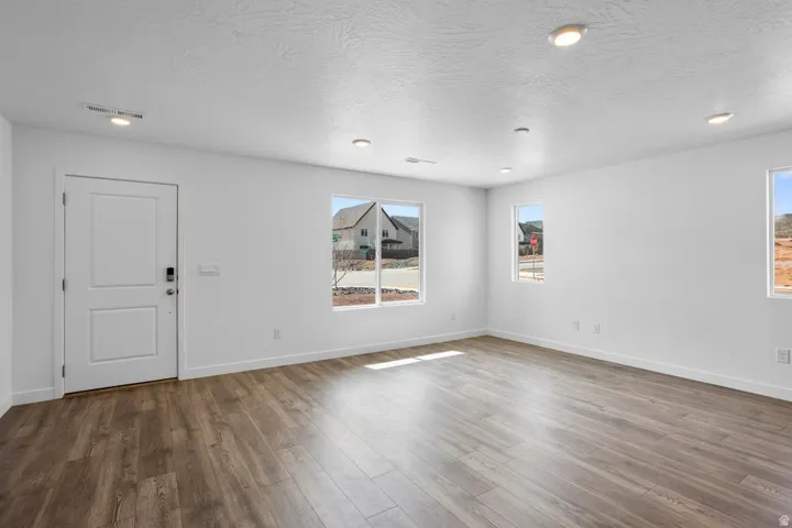 Recessed lighting, multiple windows, wood-finish flooring, white trim, and a white two-panel door