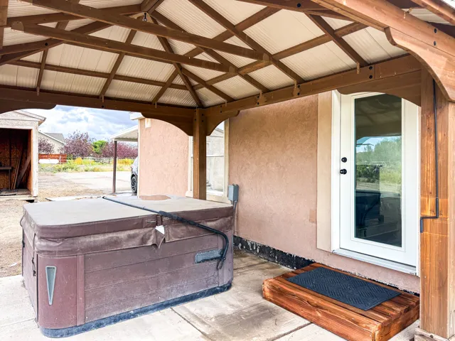 Covered patio with a spa, white exterior door, and a wood entry step
