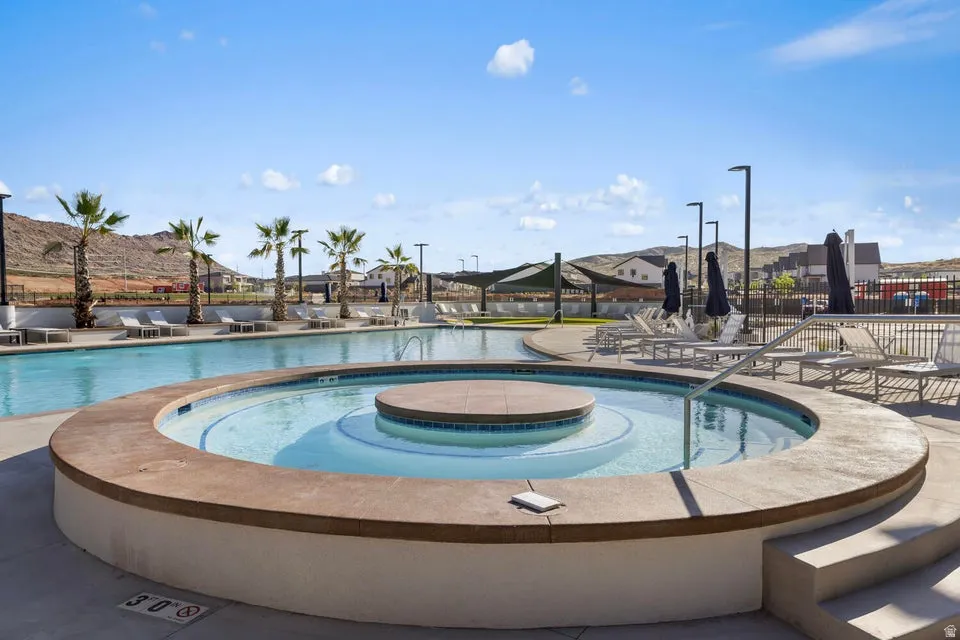Resort-style pool area featuring a large swimming pool, integrated circular spa, and concrete deck