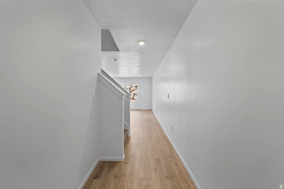 Wood-finish flooring, white walls, and recessed lighting in this hallway