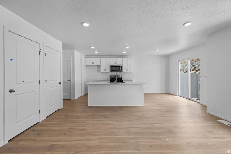 Open concept living area with wood-finish flooring, recessed lighting, and white walls