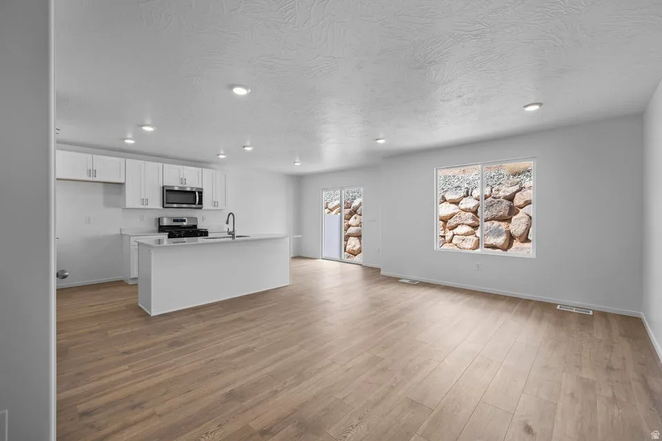 Modern kitchen featuring white cabinetry, stainless steel appliances, and a central island with a sink