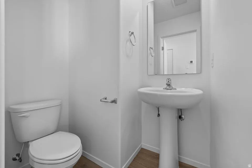 Pedestal sink, wall-mounted mirror, and wood-finish flooring