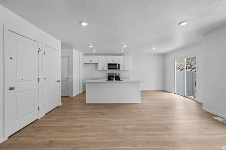 Open concept living area with wood-finish flooring, recessed lighting, and white walls