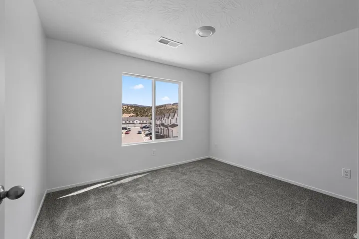 Neutral wall tones, gray carpeting, recessed ceiling light, and a window with exterior scenery