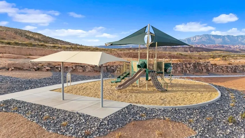 Outdoor playground with multiple slides and climbing features, shaded by a large canopy