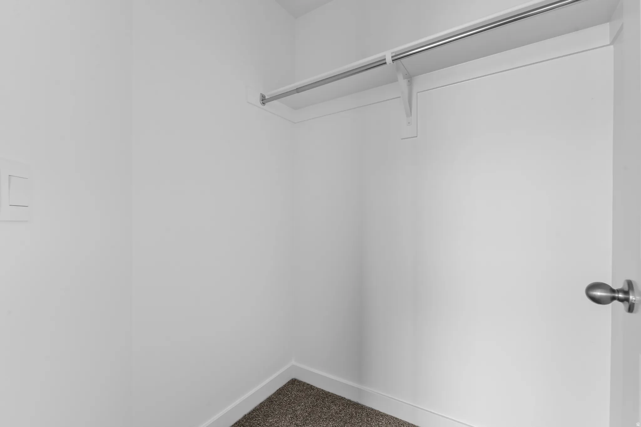Built-in closet with a metal hanging rod and carpet flooring