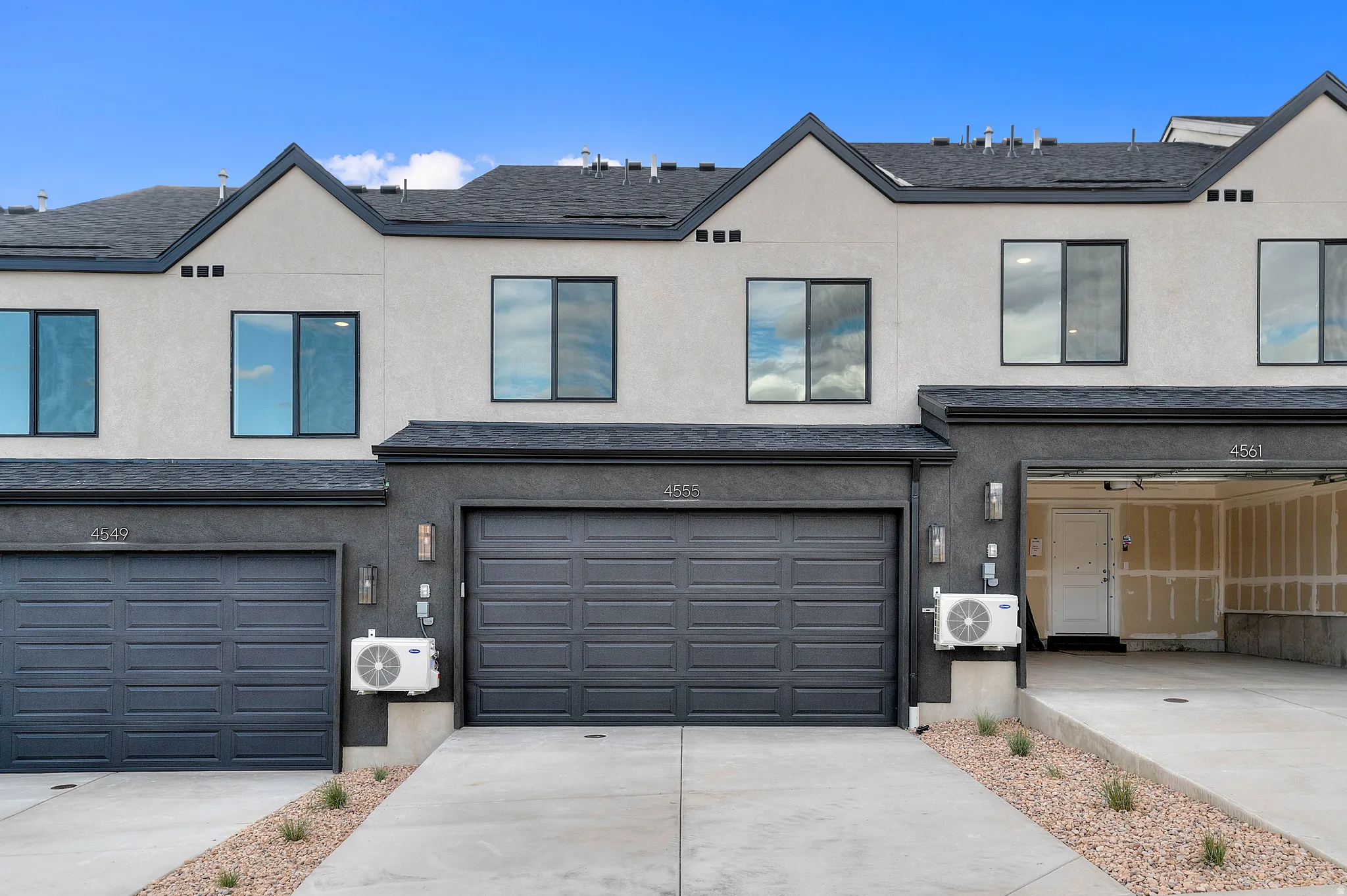 Contemporary exterior with multiple garage bays, dark framed windows, and a paved driveway