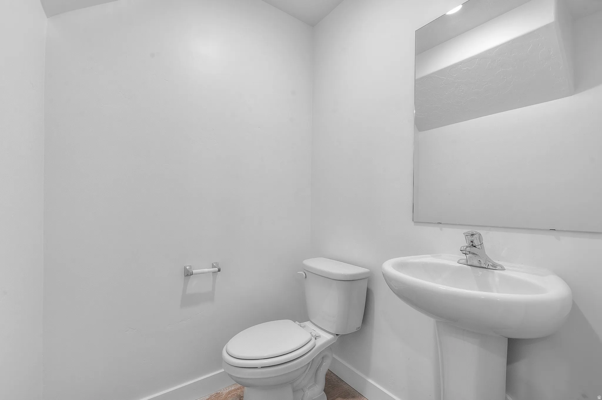 Pedestal sink with chrome-finish faucet and wall-mounted mirror