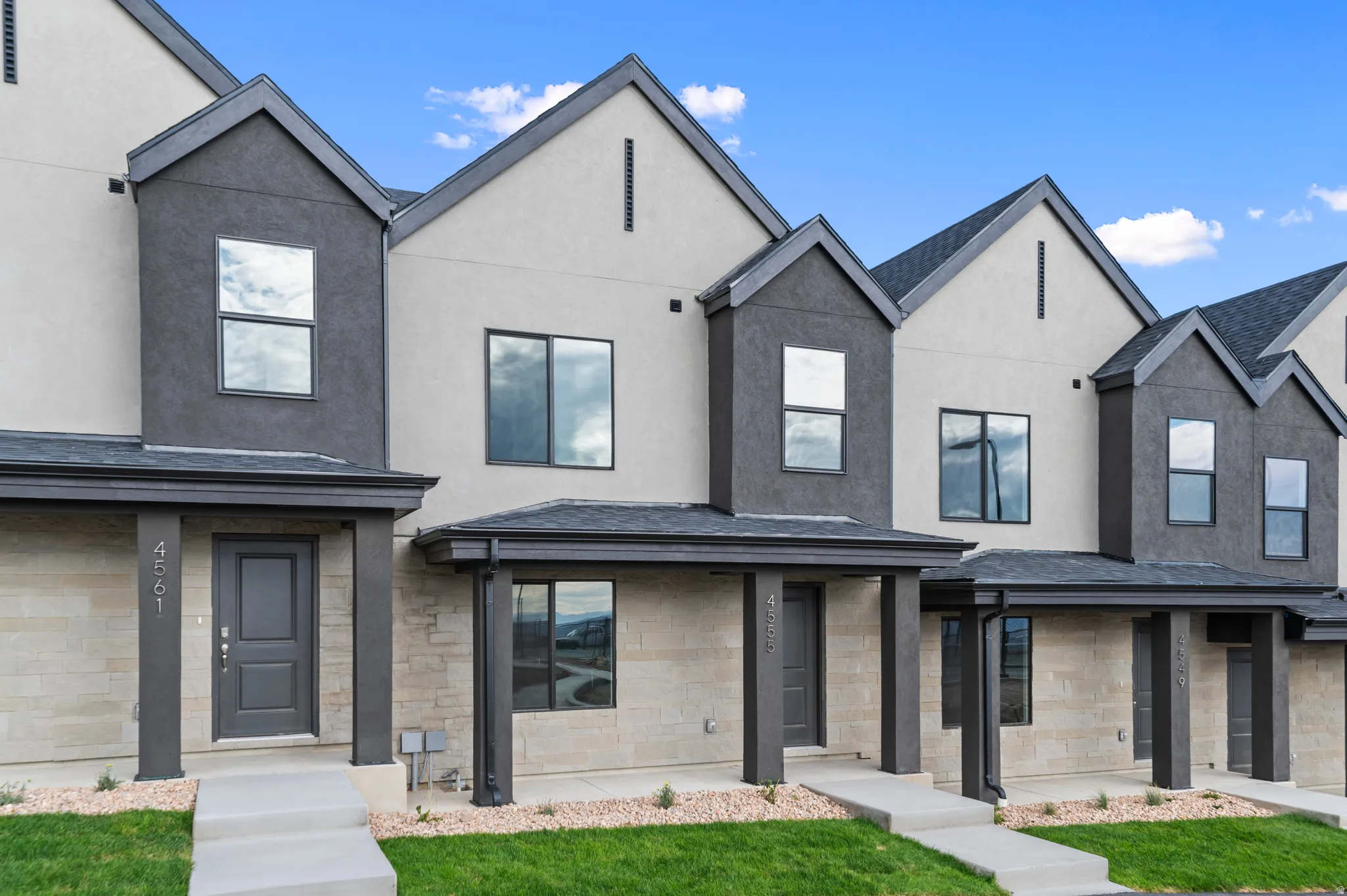 Contemporary townhome-style residences featuring a multi-tone stucco and stone facade